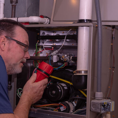 Technician examines furnace.