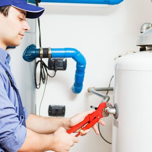 A plumber works on a tank water heater.